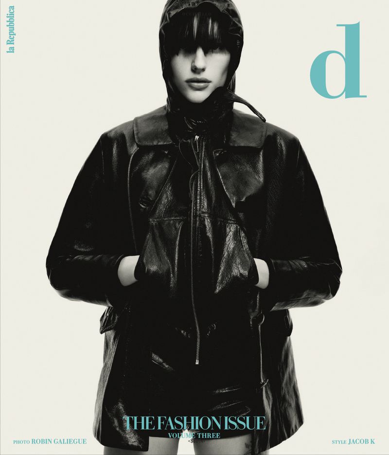 Magazine cover featuring a model in a dark, hooded, shiny jacket and skirt with a teal 'd' logo on a cream-colored background.