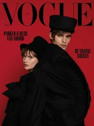 Bess and Parker Van Noord in black coats and hats against a vibrant red background for Vogue Netherlands.