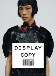 Model in black structured garment and patterned collar against a plain white background for Display Copy