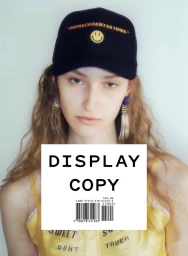 Model wearing a black embroidered cap and yellow top against a light background for Display Copy