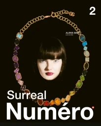 Close-up of a model surrounded by a large jeweled gold necklace against a solid black background for Numero Switzerland #2 March 2025 Covers.