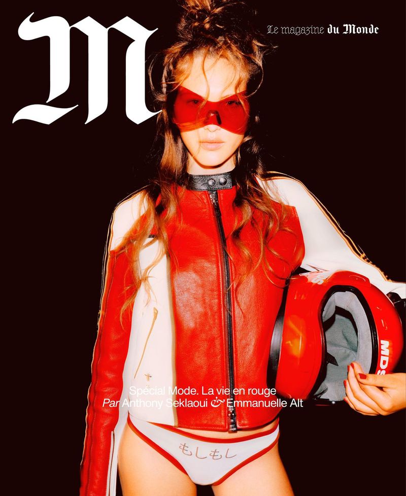 Fashion magazine cover featuring a young woman in a red racing jacket and matching eyewear holding a red helmet against a dark backdrop.