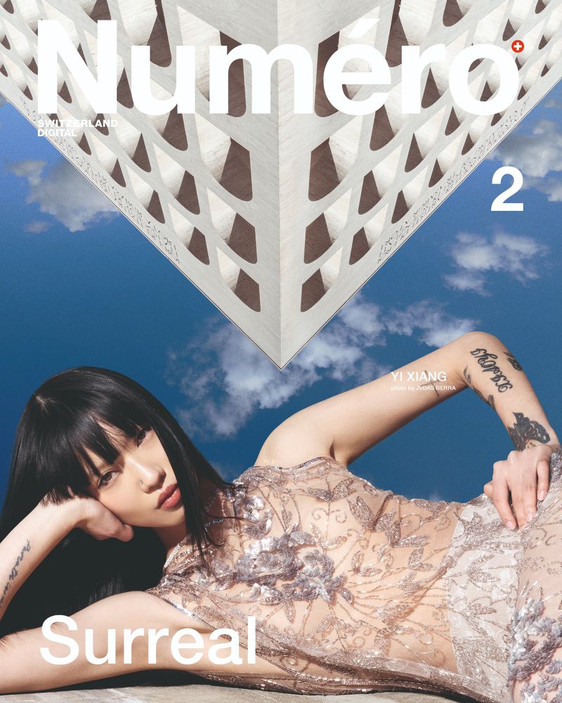 Magazine cover featuring a woman in a sheer dress, architectural element, blue sky, and the magazine's title, Numero.