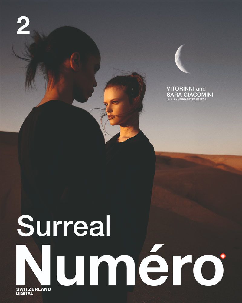 Magazine cover featuring two women embracing in a desert landscape under a crescent moon, showcasing fashion and surrealism in photography.
