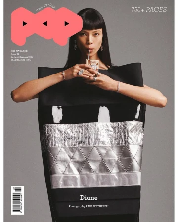 Magazine cover featuring Asian woman with bangs wearing a black dress with silver accents, drinking from a juice box with a straw.