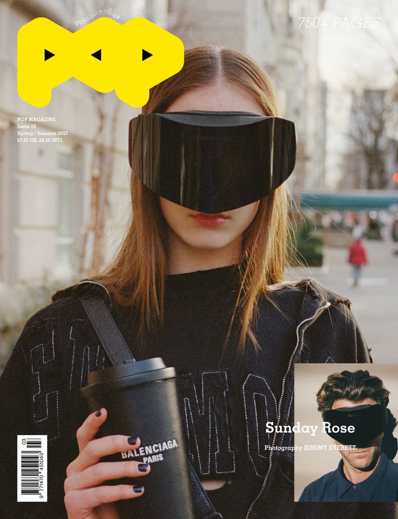 Magazine cover featuring a person with a black visor, black Balenciaga cup, and a black top, set against an urban backdrop.