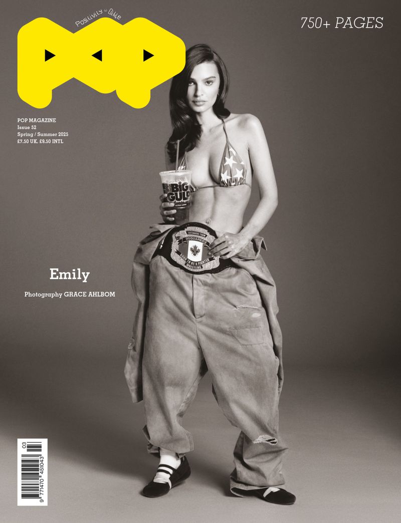 Magazine cover featuring a woman in a bikini top and oversized pants, holding a soda cup, wearing a championship belt, in studio.