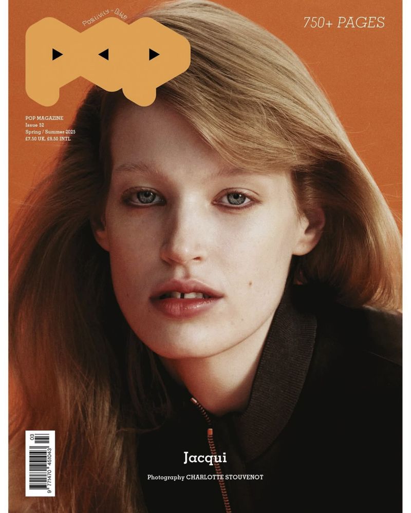 Close-up portrait of a woman with blonde hair wearing a black jacket against a solid orange background for Pop Magazine #52.