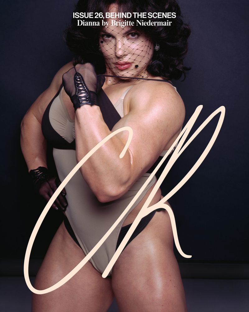 Female bodybuilder Dianna poses in a studio, wearing a vintage-style swimsuit, gloves, and a net veil, holding a leash with striking muscles.