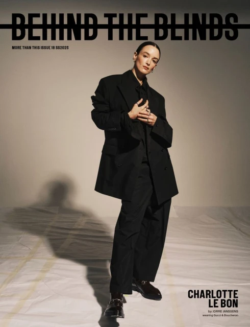 Magazine cover featuring woman in a black oversized suit, posing confidently against a soft beige backdrop, with prominent magazine title.