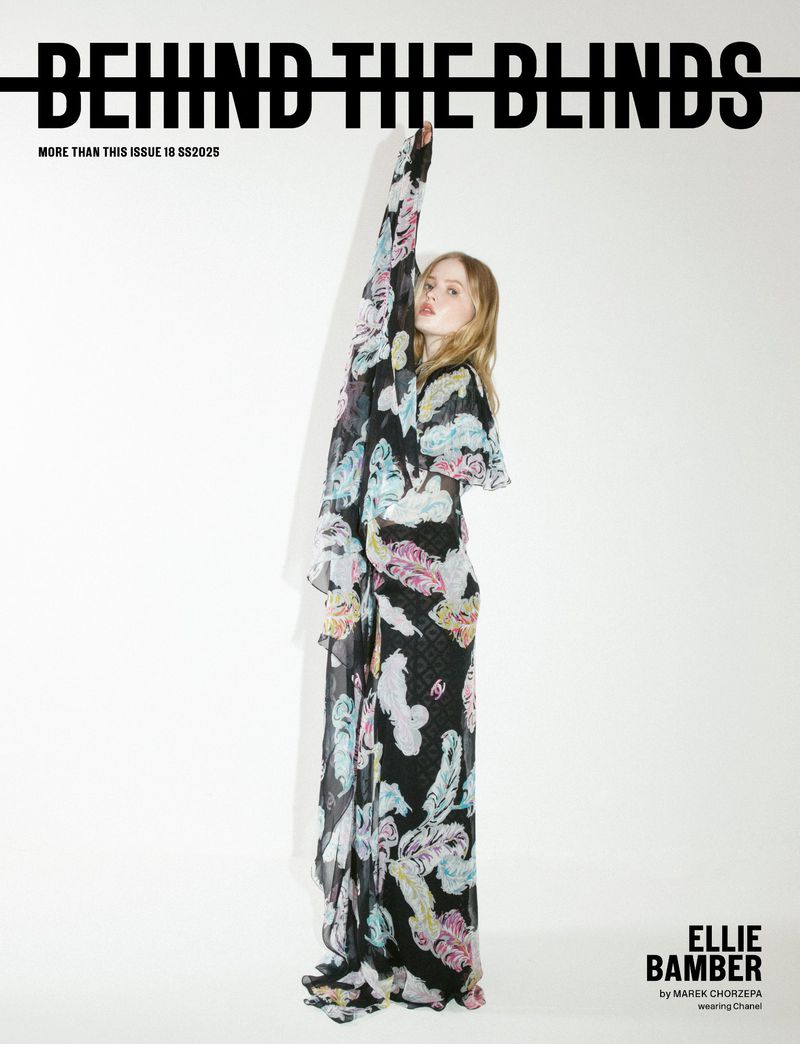 Blonde-haired model poses in a long, flowing black dress with light-colored feather patterns against a stark white background for a magazine cover.