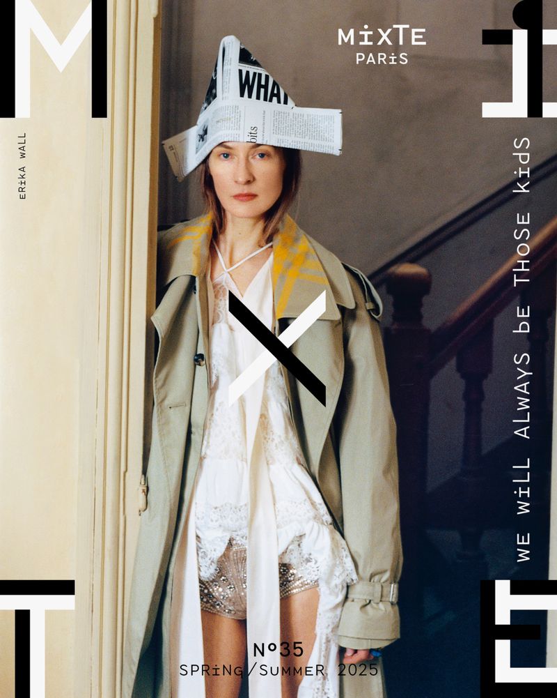 Fashion magazine cover featuring a woman in a trench coat and newspaper hat, against a staircase background with graphic design elements.