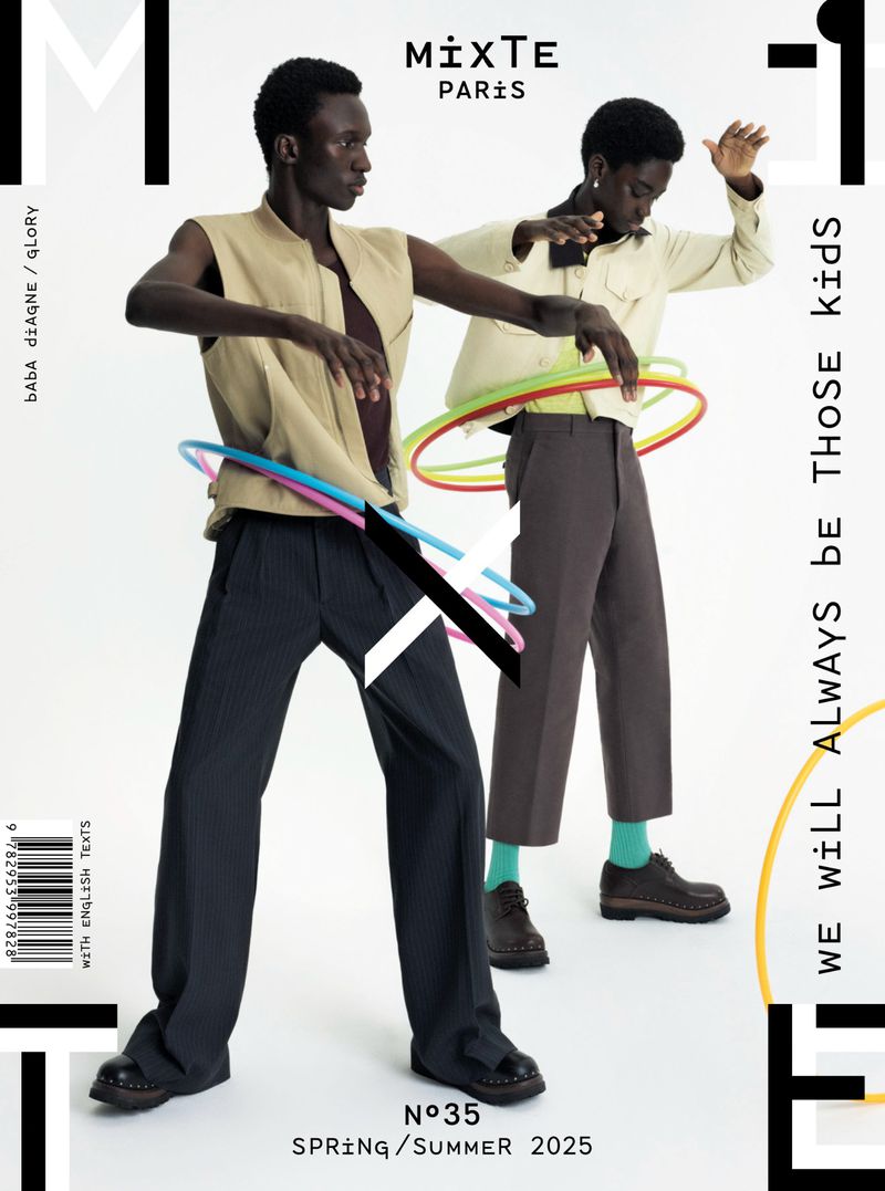 Two slender dark-skinned male fashion models in streetwear pose with hula hoops on a white background for Mixte Paris magazine, Spring/Summer 2025.
