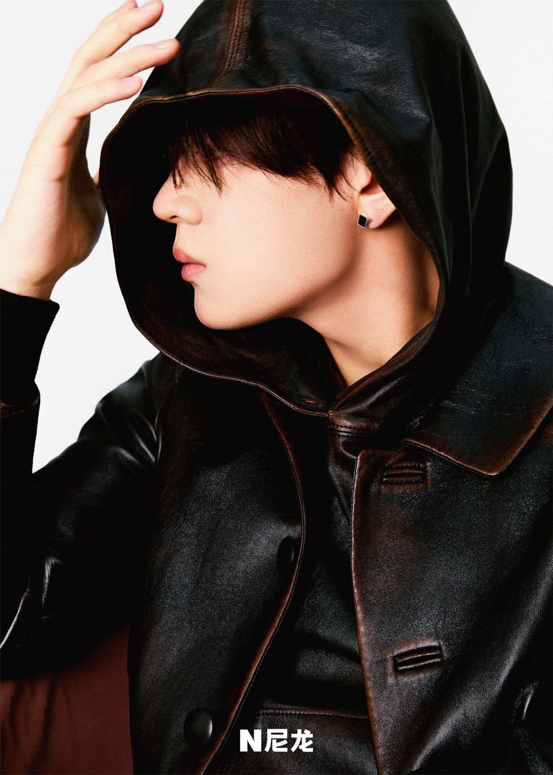 Portrait of an adult male wearing a dark hooded jacket, captured in a studio setting with soft lighting and a clean background.