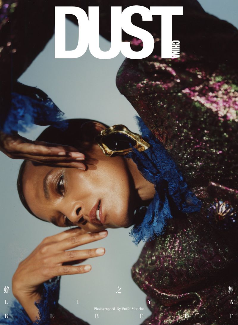 Fashion magazine cover featuring a Black woman in a sparkly, blue-trimmed outfit, striking a pose with hand gestures on a light blue background.
