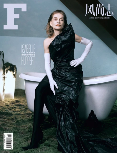 Isabelle Huppert on a magazine cover, posing in a dramatic black gown and long white gloves, sitting beside a white bathtub.