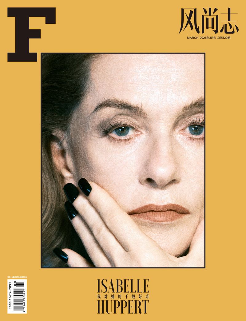 Magazine cover featuring a close-up of actress Isabelle Huppert with black nails and a tan background with a large 'F' graphic.