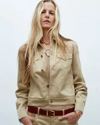 Model Emma Balfour wearing a beige jacket and brown leather belt against a white seamless background for 10 Magazine.