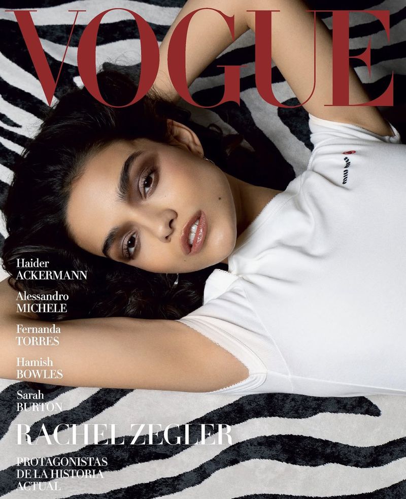 Vogue magazine cover featuring Rachel Zegler in a white top, lying on a zebra-patterned background, with the magazine title in red.