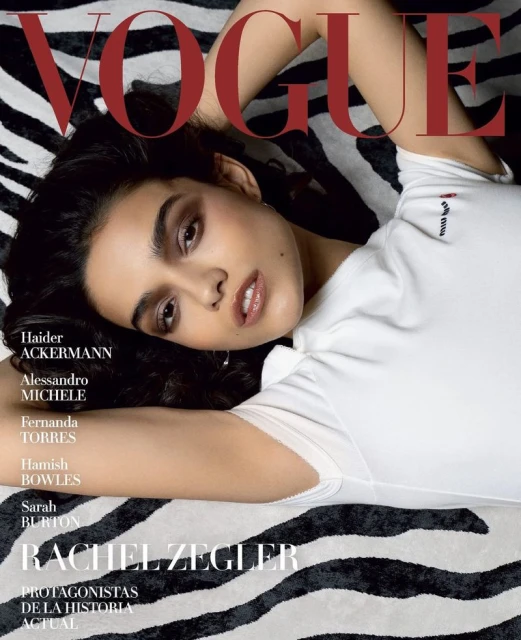 Vogue magazine cover featuring Rachel Zegler in a white top, lying on a zebra-patterned background, with the magazine title in red.