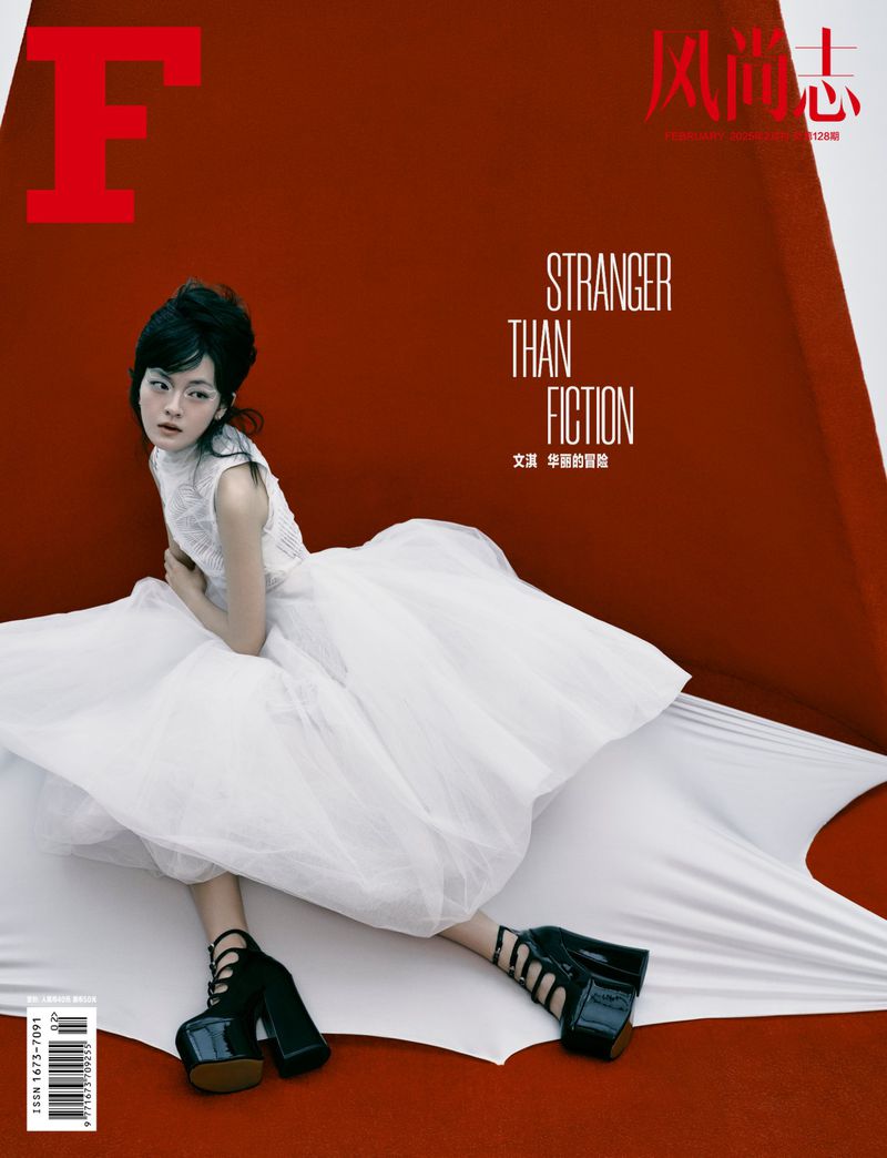 Magazine cover featuring a young woman in a white dress and black platform shoes against a red background with white draped fabric.