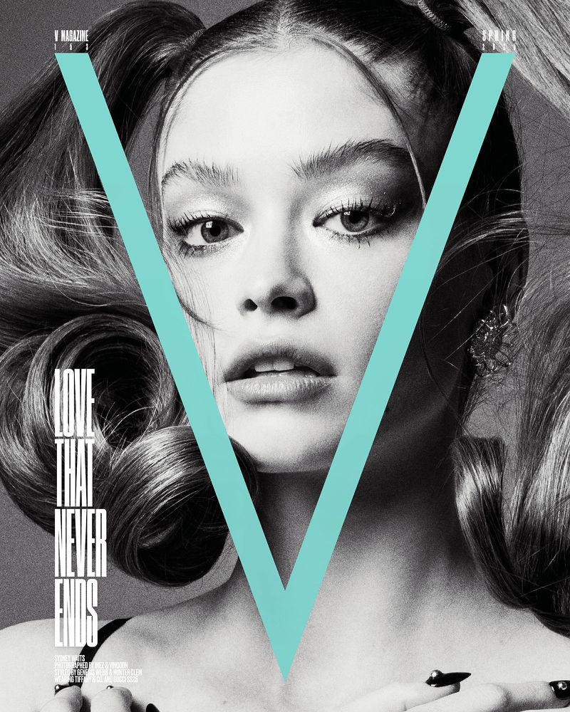 Monochrome portrait of a young woman with pigtails, heavy makeup, and a large letter 'V' superimposed on her face, jewelry and manicure.