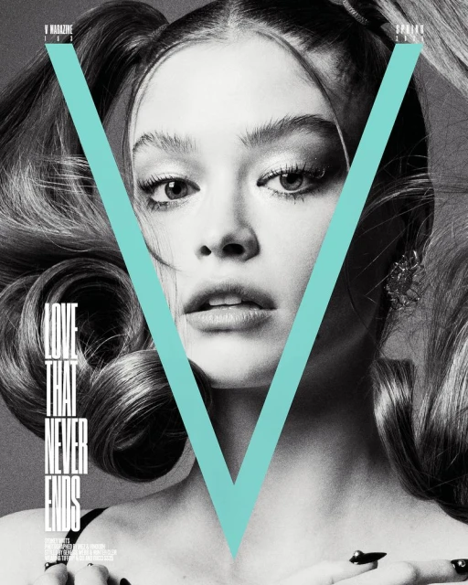 Monochrome portrait of a young woman with pigtails, heavy makeup, and a large letter 'V' superimposed on her face, jewelry and manicure.