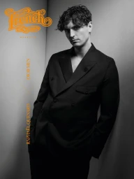 Monochrome portrait of a man in a black double-breasted suit against a neutral background for French Magazine.