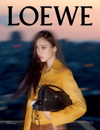 Fashion portrait featuring an Asian female model showcasing a Loewe handbag, wearing a mustard yellow jacket and brown leather pants against an outdoor backdrop.