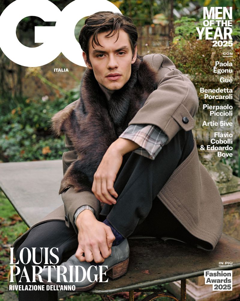 Magazine cover featuring Louis Partridge in a coat with fur collar, seated on a metal bench, promoting GQ Italia's 'Men of the Year'.