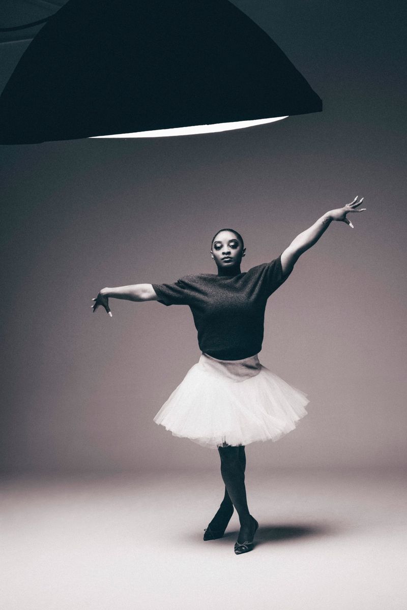 Young woman in ballet pose wearing tutu in studio under lighting equipment. Dance or fashion photography with ballerina in studio.
