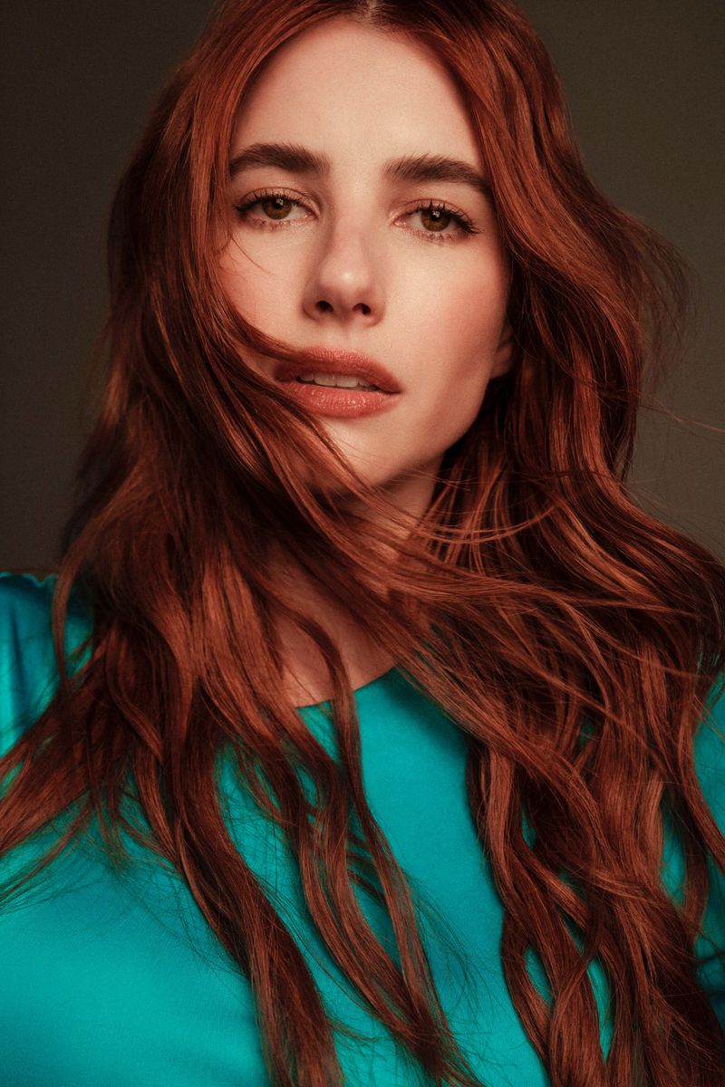Portrait of a woman with long red hair wearing a blue top. Studio lighting creates a clean and professional fashion-style image.