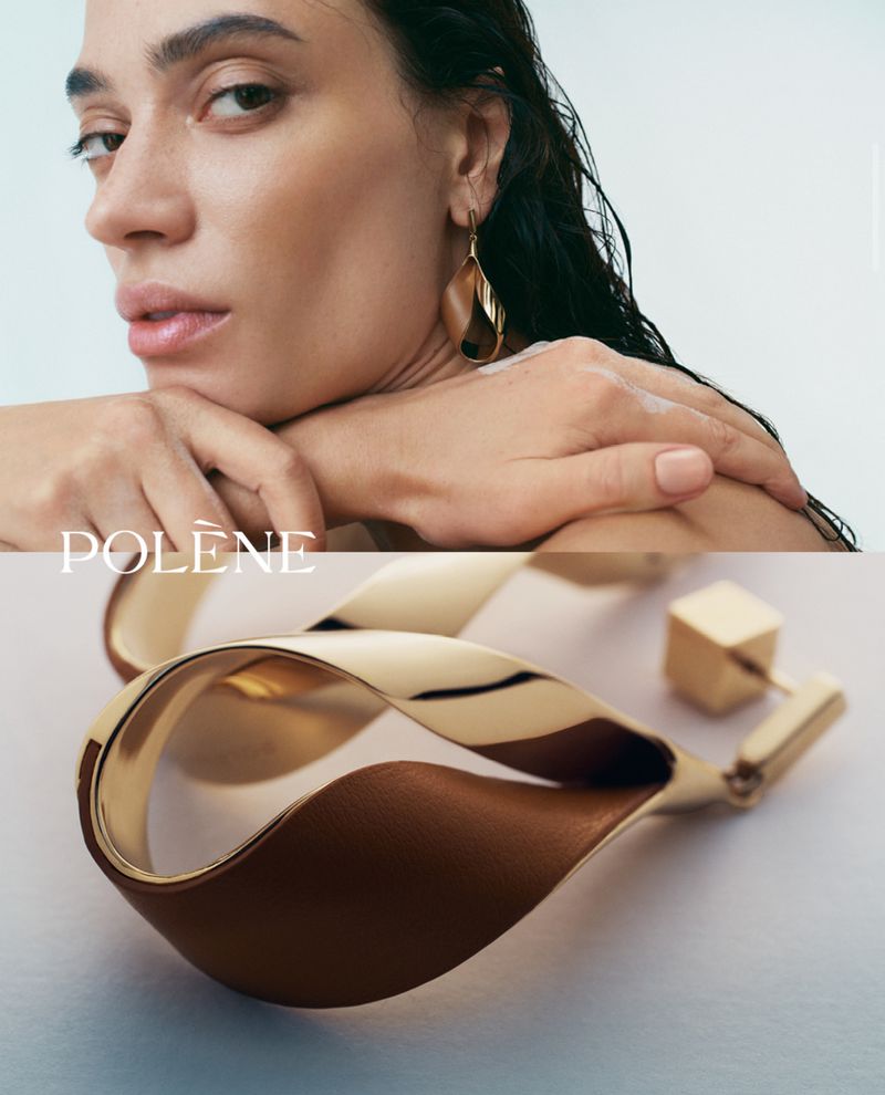 Close-up studio shot of adult female model wearing large gold earrings with geometric shape, against a neutral background.
