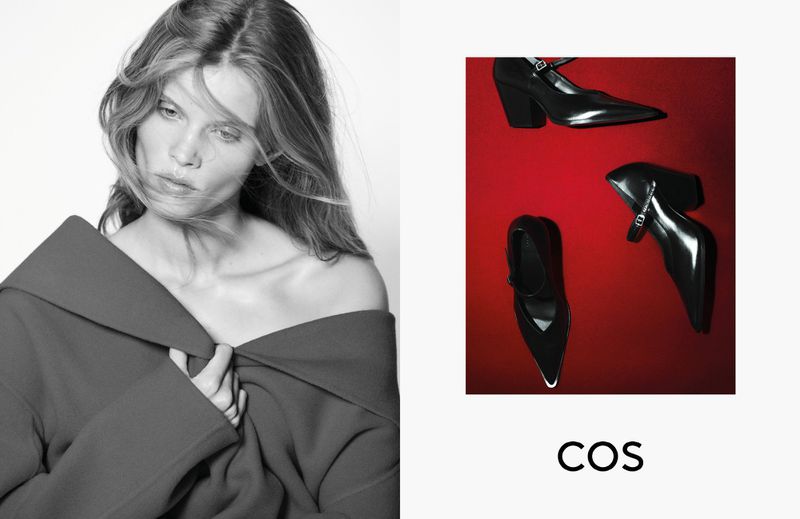 Fashion editorial shot of a woman in an off-shoulder jacket alongside three black, heeled, Mary Jane shoes on a red background.