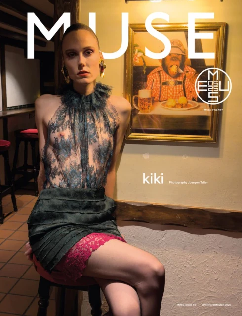 Fashion magazine cover featuring a fair-skinned young adult woman in a lace-detailed top and dark skirt, posed next to a framed painting.