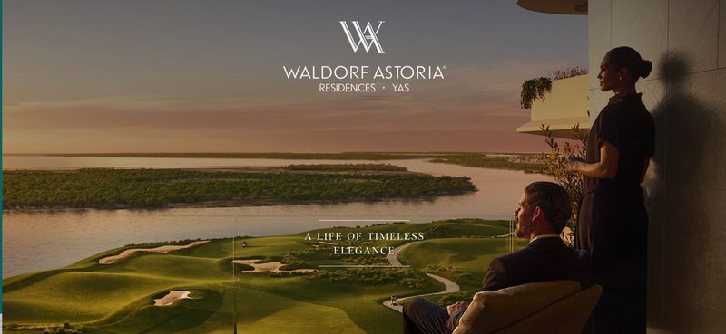 Man and woman overlooking a golf course, river, and trees at sunset from a modern apartment. Waldorf Astoria Residences ad.
