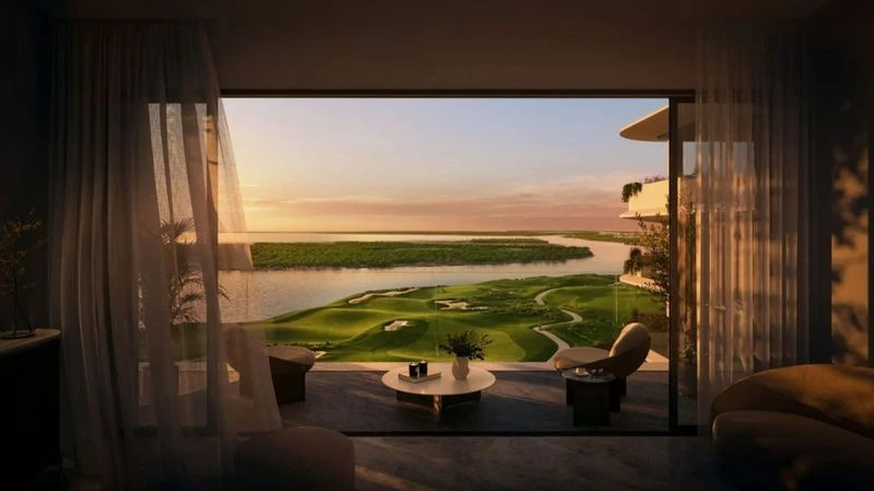 Scenic view from a modern apartment balcony overlooking a lush green golf course and river at sunset with sheer curtains.