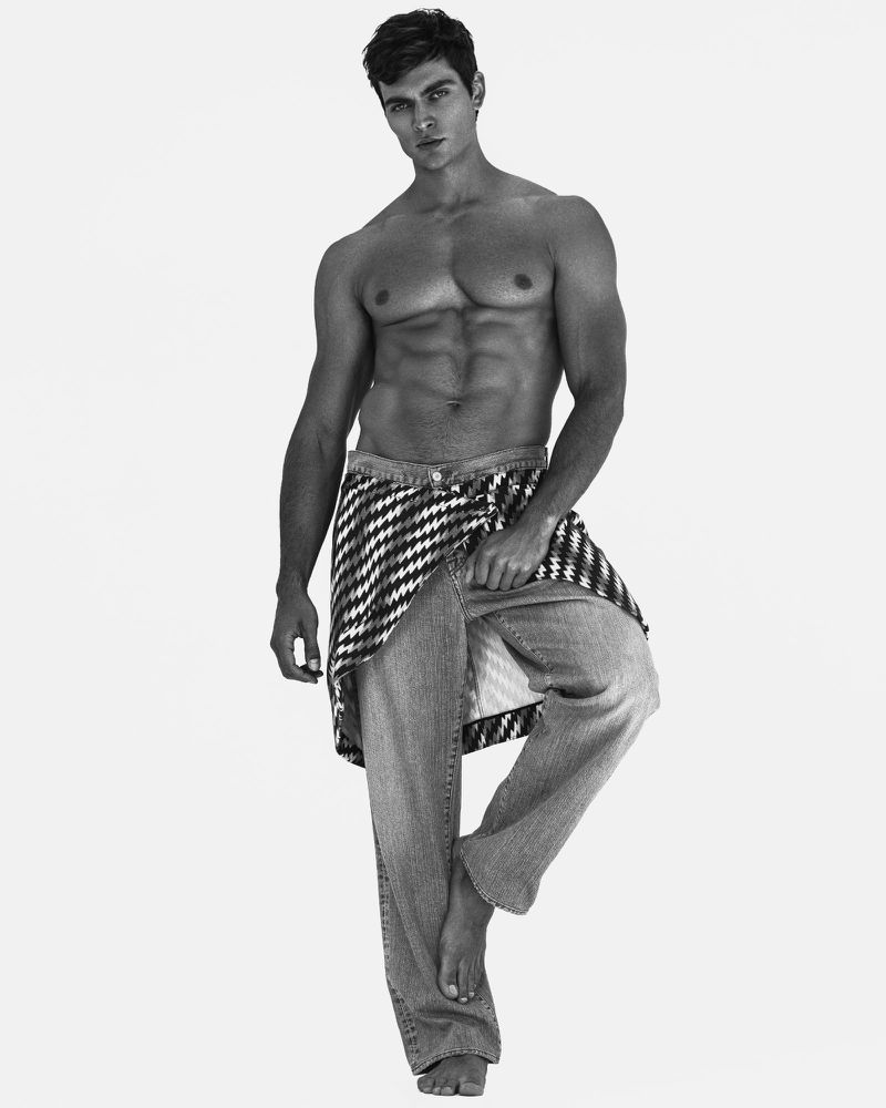 Black and white portrait of a shirtless adult male with defined musculature, jeans, and a patterned shirt tied around his waist.