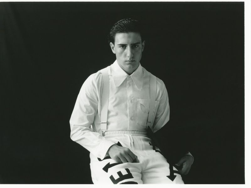 Monochrome portrait of a young man wearing a white shirt and suspenders against a dark background for SSAW Magazine