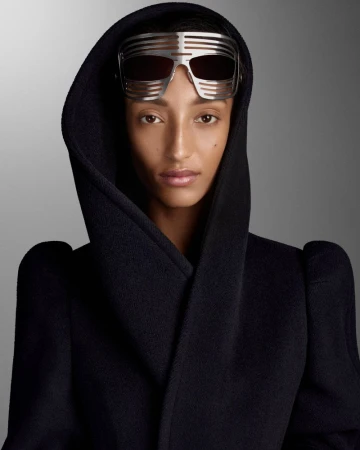 Mona Tougaard wearing a black hooded coat and futuristic silver slat sunglasses against a grey backdrop for D Repubblica