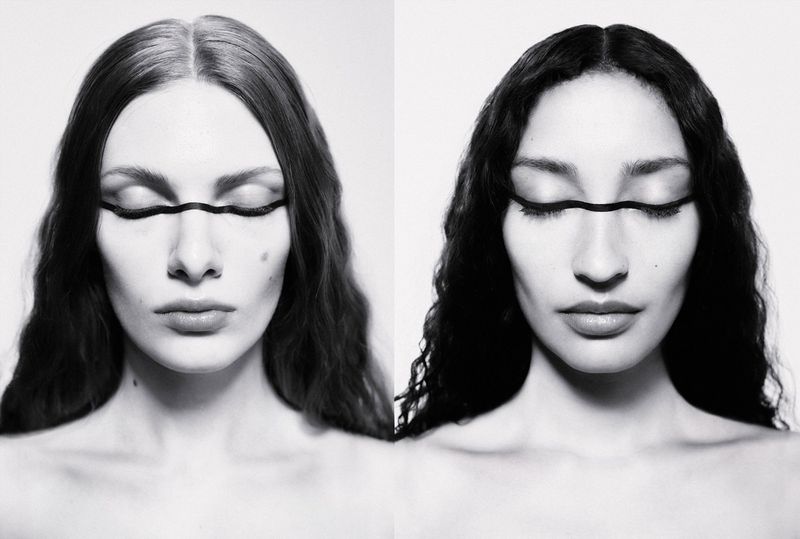 Monochrome portrait of two women with closed eyes, wearing a black decorative band over their eyes in a beauty or fashion editorial.