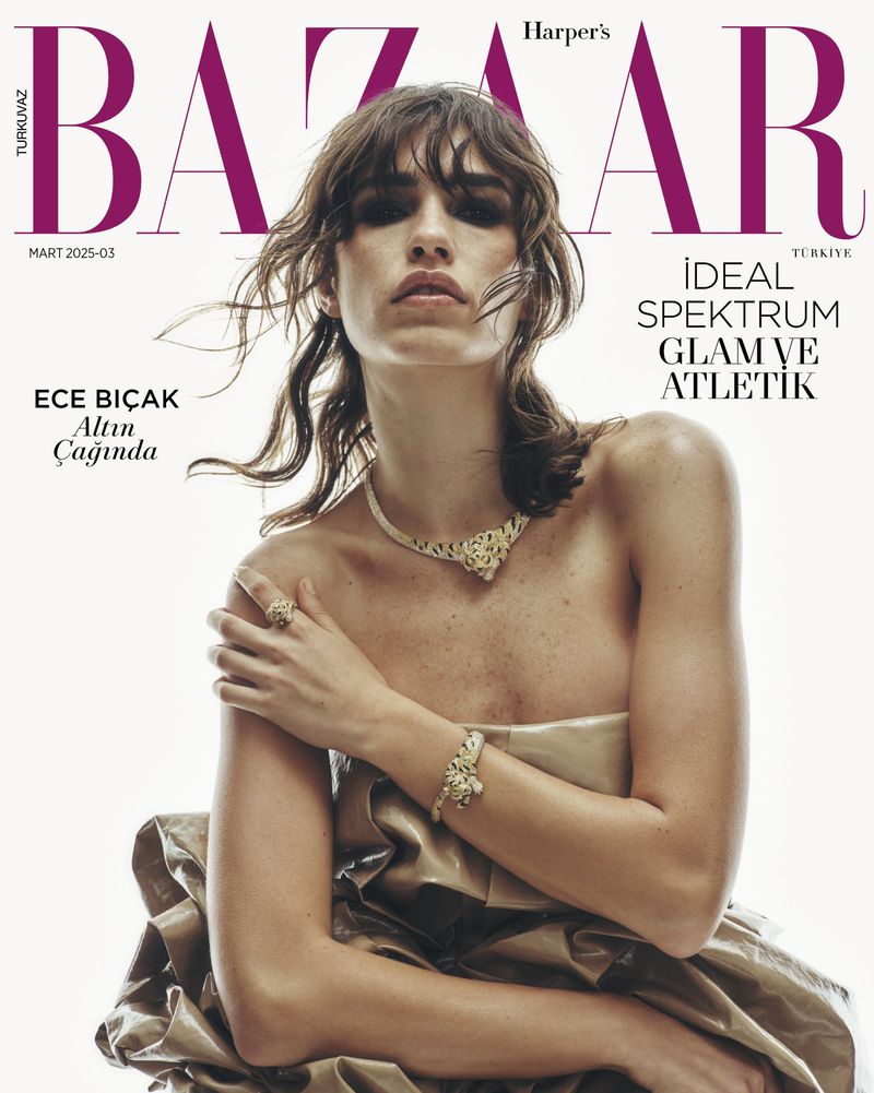 Harper's Bazaar magazine cover featuring a brunette woman wearing gold jewelry and a gold draped garment against a white background.