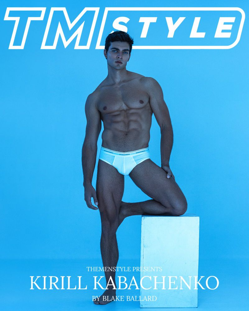 Fashion shot of a shirtless male model in underwear, posing against a light blue backdrop with a white cube and magazine cover text.