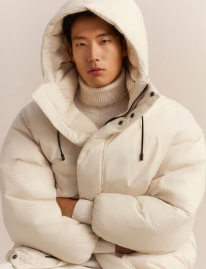 Asian male model wearing a white hooded puffer jacket and turtleneck sweater against a neutral background