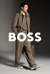 Model Juhyung Kang in a brown jacket and trousers against a grey seamless studio background with BOSS branding overlay