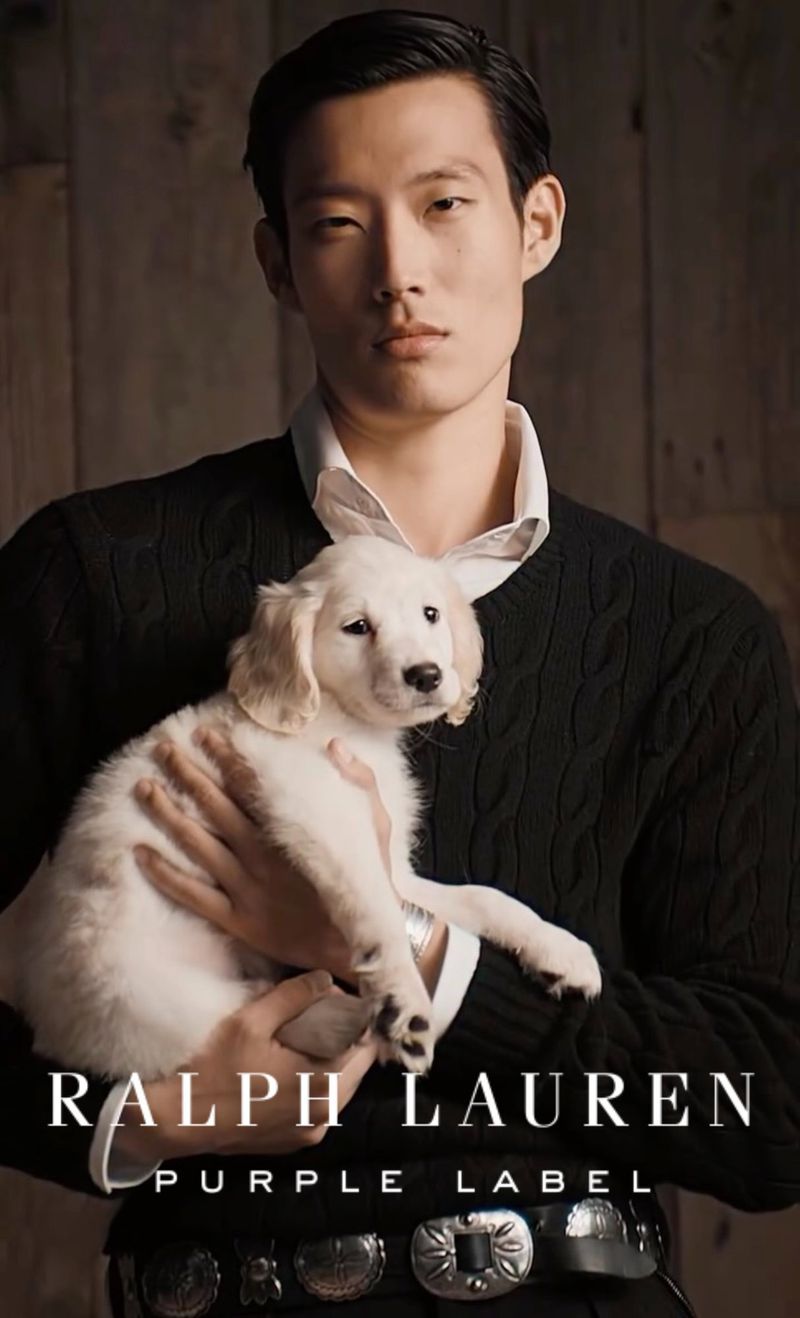 Asian man holds Golden Retriever puppy in a fashion shot for Ralph Lauren Purple Label, showcasing the brand's classic style.