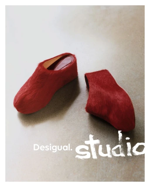Two red, furry Desigual Studio heeled shoes displayed in a minimalist fashion product shot on a neutral surface with soft, diffused lighting.