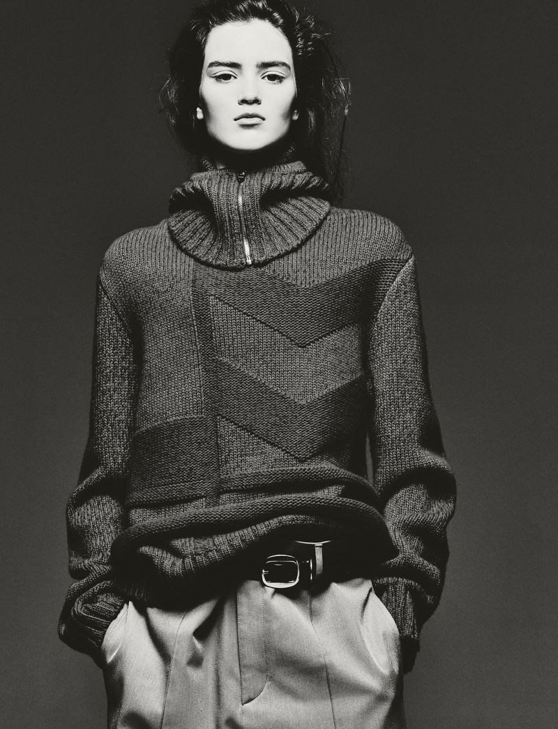 Model Niamh Battersby wearing a high-neck patterned knit sweater in a black and white editorial portrait.