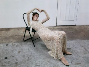 Model Sophia Roberts in a long lace dress reclining on a black metal chair for Elle x Dior, featuring hair styling by Michele McQuillan.