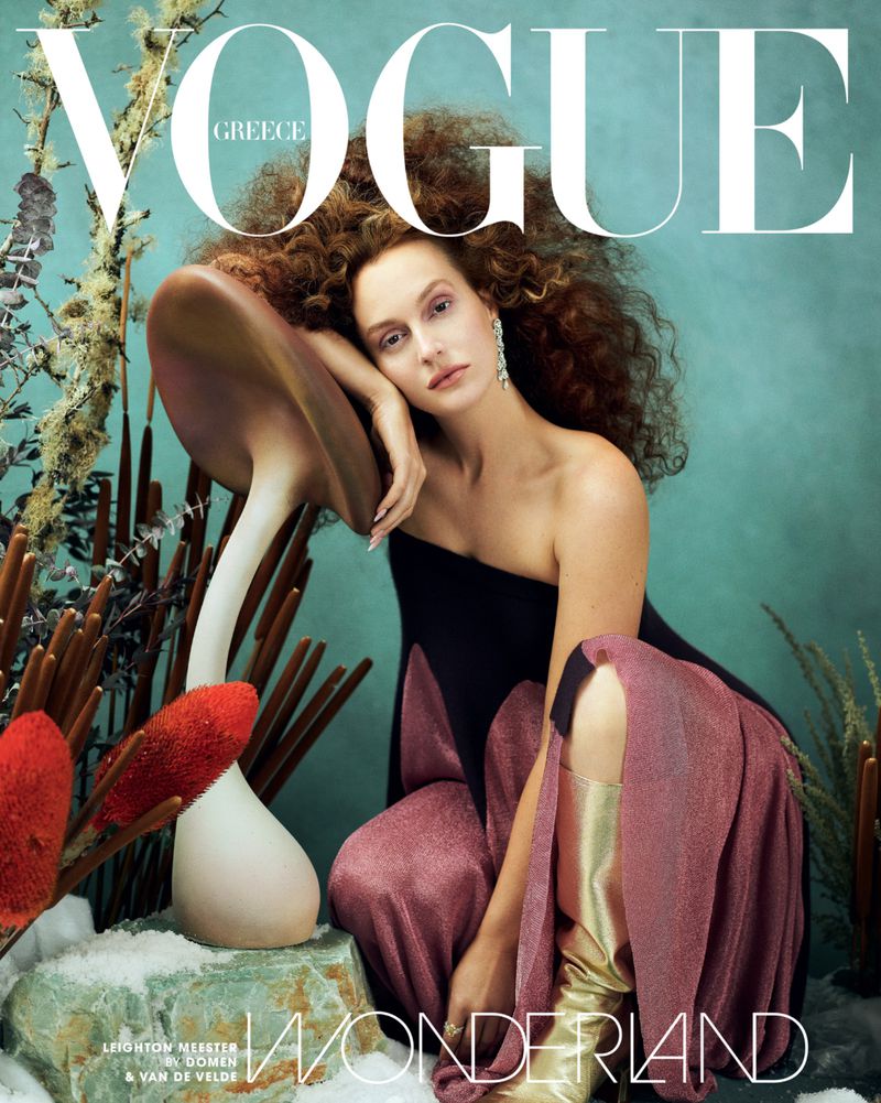 Vogue Greece cover featuring a model with curly red hair in a black and pink dress, kneeling beside a giant mushroom.